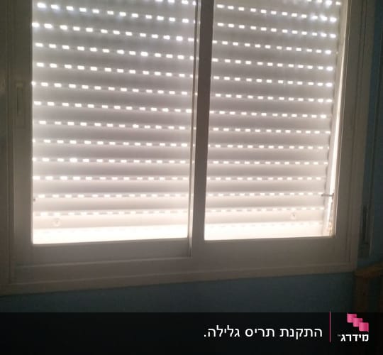 תריסים סגורים עם חריצים לאור בחלון כפול